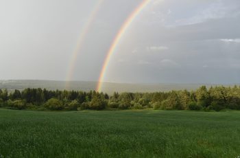 Photo par Claude Laprise two rainbows in the sky over a green field